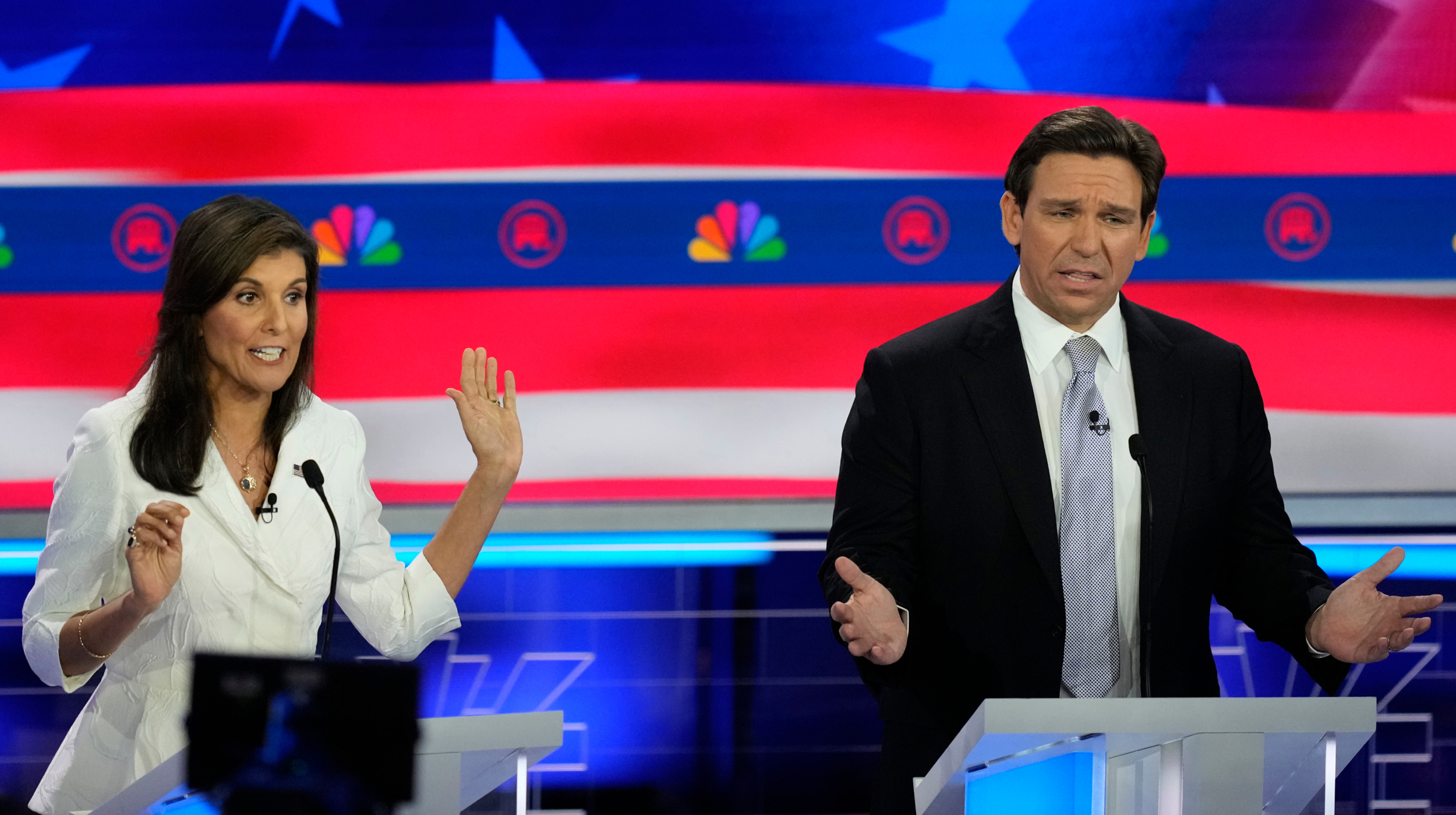 A man and woman standing at a podium in front of an american flag.