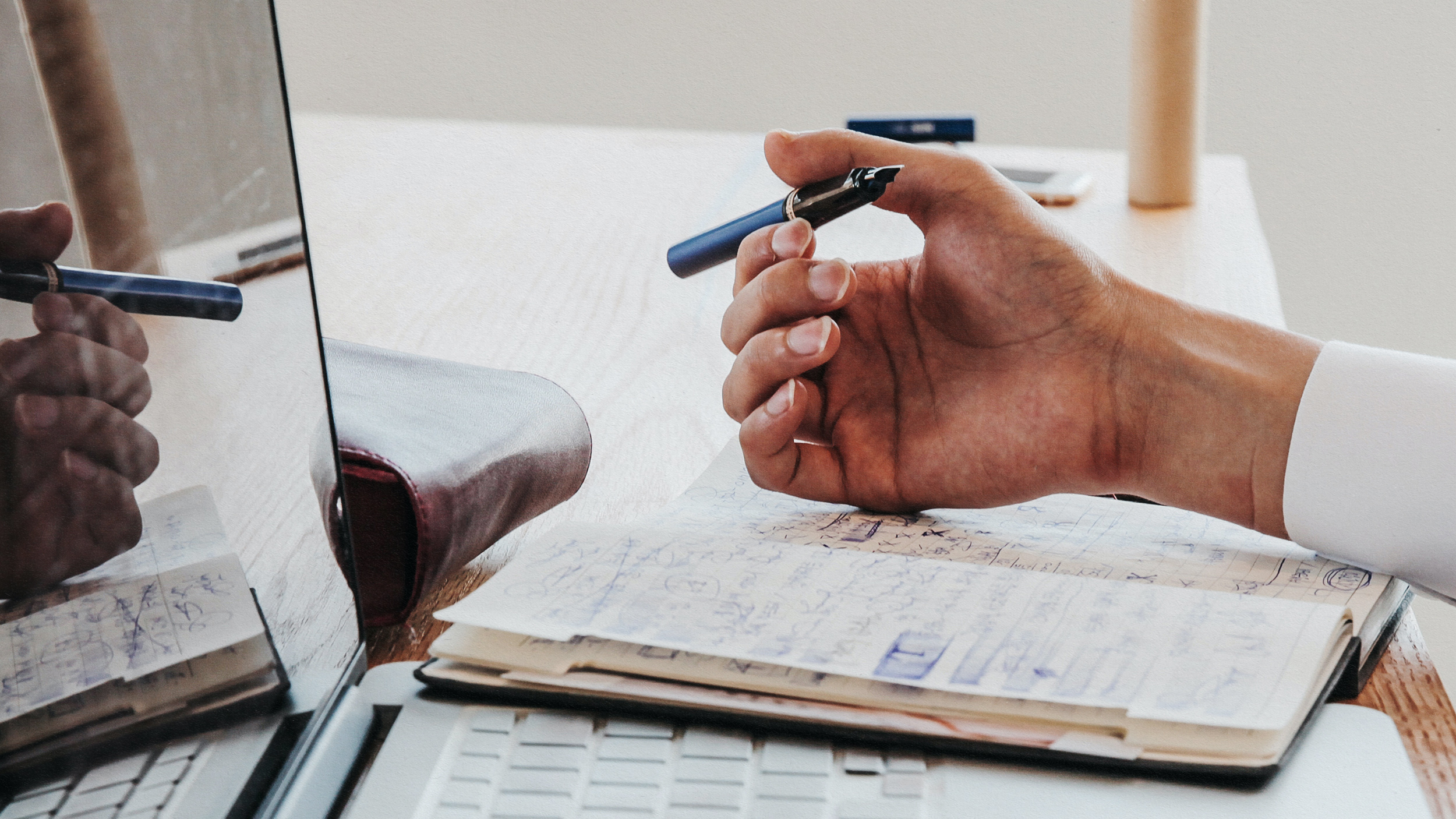 A post-career world with a desk holding a laptop and hand holding a pen.