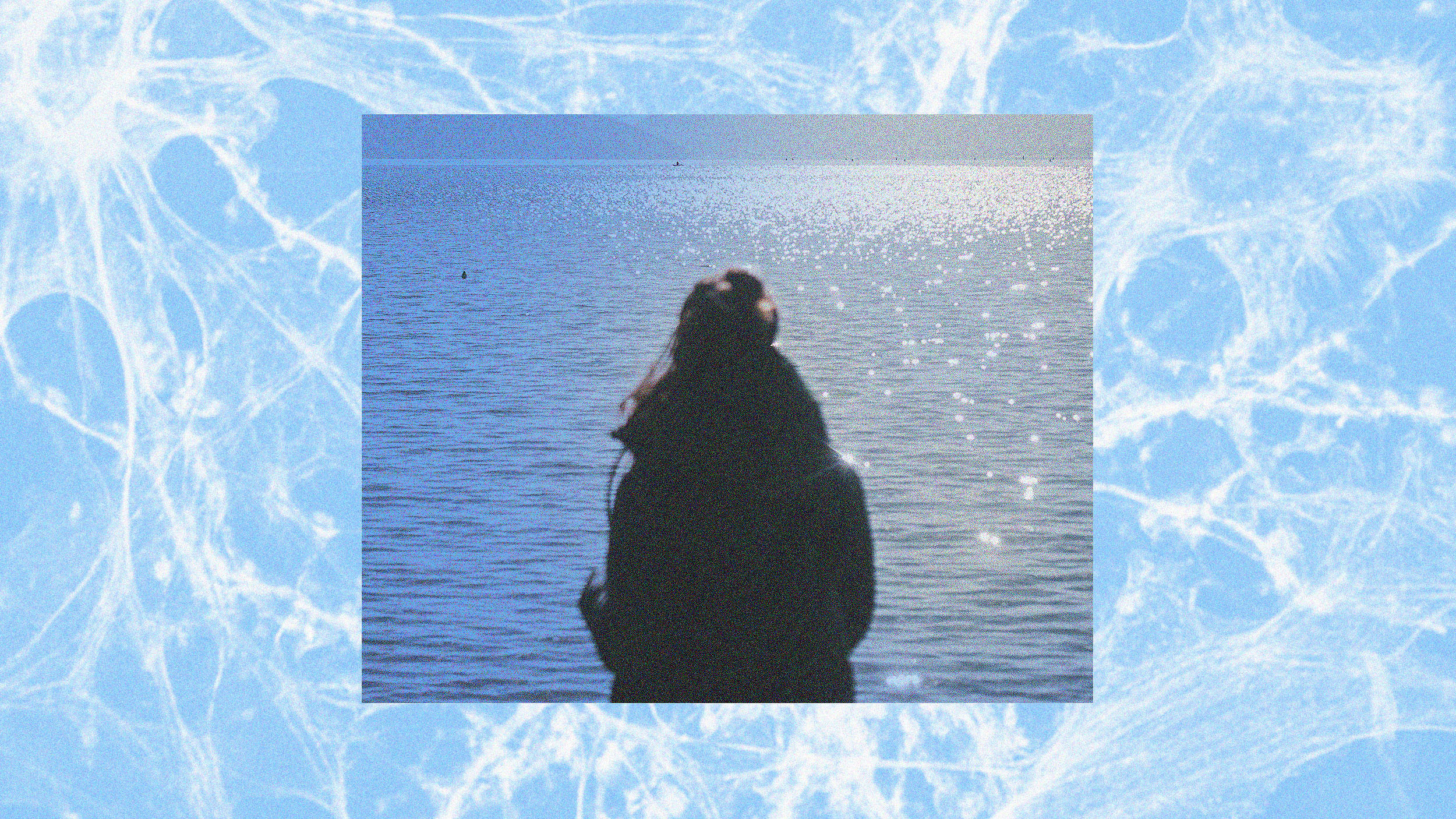 A photo capturing the memory of a woman standing in front of a body of water.